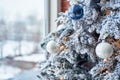 Closeup of Christmas tree decorated with white baubles and garland near window, copy space. Christmas decorations. Holiday Royalty Free Stock Photo