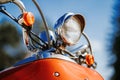 Closeup chrome detail and headlamp of orange retro vintage scooter under blue sky and sun on the blurred background. Royalty Free Stock Photo