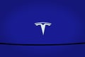 Closeup chromium-plated Logotype Tesla Motors on blue hood, most popular passenger electric car in world, Elon Musk, Tesla is