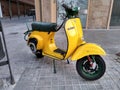 Closeup of a classic yellow Piaggio Vespa scooter on the street