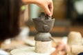 Closeup clay work with hand of girl decorating her work by putting mud with blurred foreground and background