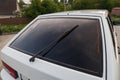 Closeup of a clean rear tinted black glass of a Russian white car with a wiper and a red brake light. Presale preparation of a