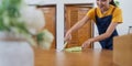Closeup cleaning woman sweeping wooden table with small whisk broom and dustpan in living room Royalty Free Stock Photo