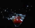 Closeup of a cocktail with a strawberry in a glass and water splash on a black background Royalty Free Stock Photo