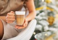 Closeup on coffee in hand of woman in front of christmas tree Royalty Free Stock Photo