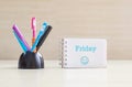 Closeup color pen with black ceramic desk tidy for pen and blue friday word in white page and happy face emotion at the note book Royalty Free Stock Photo