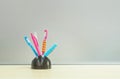 Closeup color pen with black ceramic desk tidy for pen on blurred wooden desk and frosted glass wall textured background in the Royalty Free Stock Photo