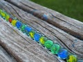 Closeup of colorful glass marbles on a wooden bench in a park Royalty Free Stock Photo