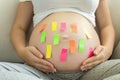 Closeup of colorful memo stickers on pregnant woman tummy