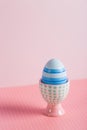 Closeup colorful painted Easter egg in vibrant modern egg stand on pastel pink background