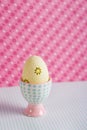 Closeup colorful painted Easter egg in vibrant modern egg stand on spotted pink background