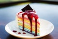 Closeup of colorful rainbow crape cake on white plate , serving with strawberry sauce topping Royalty Free Stock Photo