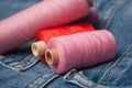 colorful sewing thread spool bobbins on blue jeans background Royalty Free Stock Photo