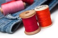 Colorful sewing thread spool bobbins on white table on blue jeans background Royalty Free Stock Photo