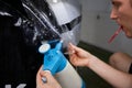 Closeup concentrated man worker smoothing protective film in car garage