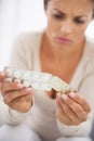 Closeup on concerned young woman studying pills