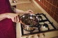 Closeup of chocolatier with wooden spatula heating and melting chocolate in water bath on a stove in the kitchen