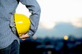 Closeup of a construction worker holding a yellow safety helmet on blurred background Royalty Free Stock Photo