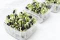 Closeup of containers full of growing greens, sunflower microgreens on the white surface