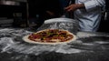 Closeup of a cook taking a whole raw pizza with a peel in the kitchen