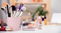 Closeup cosmetic kit makeup brushes in pink cup, white background copy space banner