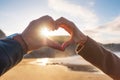 Closeup of couple hands making heart shape in the beach, in autumn season. Happy couple in love. Royalty Free Stock Photo