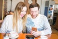 Closeup of couple listening to music with mobile phone at coffee bar. Man and woman listening music with headphones. Royalty Free Stock Photo