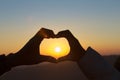 Closeup of couple making heart shape with hands and sunrise background, Happy in love Royalty Free Stock Photo