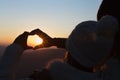 Closeup of couple making heart shape with hands and sunrise background, Couple in love, Focus on hands, Man and woman tourists in