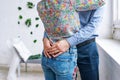 Closeup of couple at the white room. Man in a formal wear hugging by the waist a woman, wearing jeans Royalty Free Stock Photo