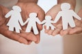Closeup of a couples hands holding paper cutout of a perfect family. Symbol of home cover, insurance, health, adoption