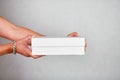 Closeup courier hand hold empty cardboard box on grey background studio,