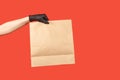 Closeup courier hand in protective gloves holding grocery paper bag, safe delivery service in protective gloves