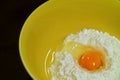 Closeup cracked egg on raw flour in a yellow mixing bowl Royalty Free Stock Photo