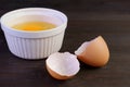 Closeup cracked eggshell on dark brown wooden table with raw egg bowl in the backdrop Royalty Free Stock Photo