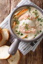 Closeup of creamy fish soup with cod, salmon, carrot and celery in a bowl served with fresh bread. Vertical top view Royalty Free Stock Photo