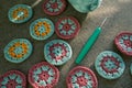 Closeup of crochet circles and a hook with part view of cotton skein on grey textured fabric in hard light and shadows