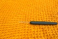 Closeup of crochet hook with black handle lieing on bright yellow crochet net texture Royalty Free Stock Photo