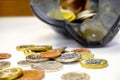 Closeup and crop of British currency coins open from the piggy bank laid out scattered on white table