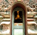 A golden buddha through the arch of temple