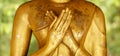 Closeup and crop hands of golden Buddha statue on blurred background