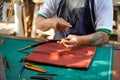 Closeup and crop hands of leather craftsman sewing a leather brown bag for a customer