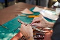 Closeup and crop hands of leather craftsman sewing a leather brown bag for a customer