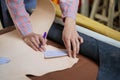 Closeup and crop hands of young female leather goods maker is drawing a design on leather