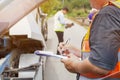 Closeup and crop insurance agent writing on clipboard while examining car after accident claim being assessed and processed on