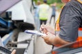 Closeup and crop insurance agent writing on clipboard while examining car after accident claim being assessed