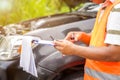 Closeup and crop insurance agent writing on clipboard while examining car after accident claim being assessed and processed