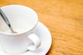 Closeup and crop white coffee cup and spoon with saucer on wooden table Royalty Free Stock Photo