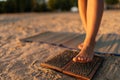 Closeup cropped shot of feet unrecognizable female stepping on Sadhu Nail board during meditation practice on sandy