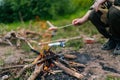 Closeup cropped shot of unrecognizable tourist male grilling sausages on campfire in countryside. Traveler cooking food Royalty Free Stock Photo